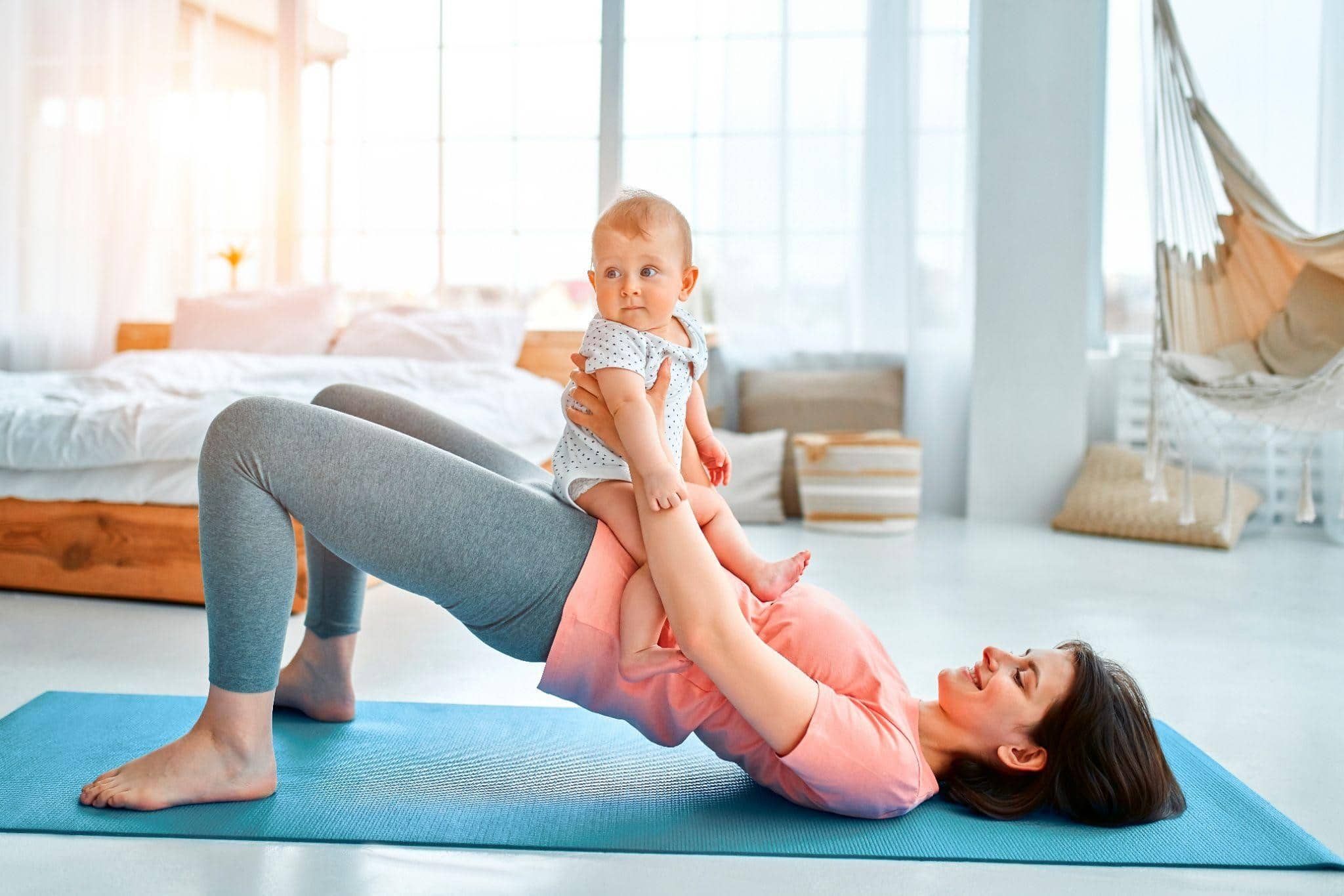 Mother exercising with her child, focusing on postpartum recovery.