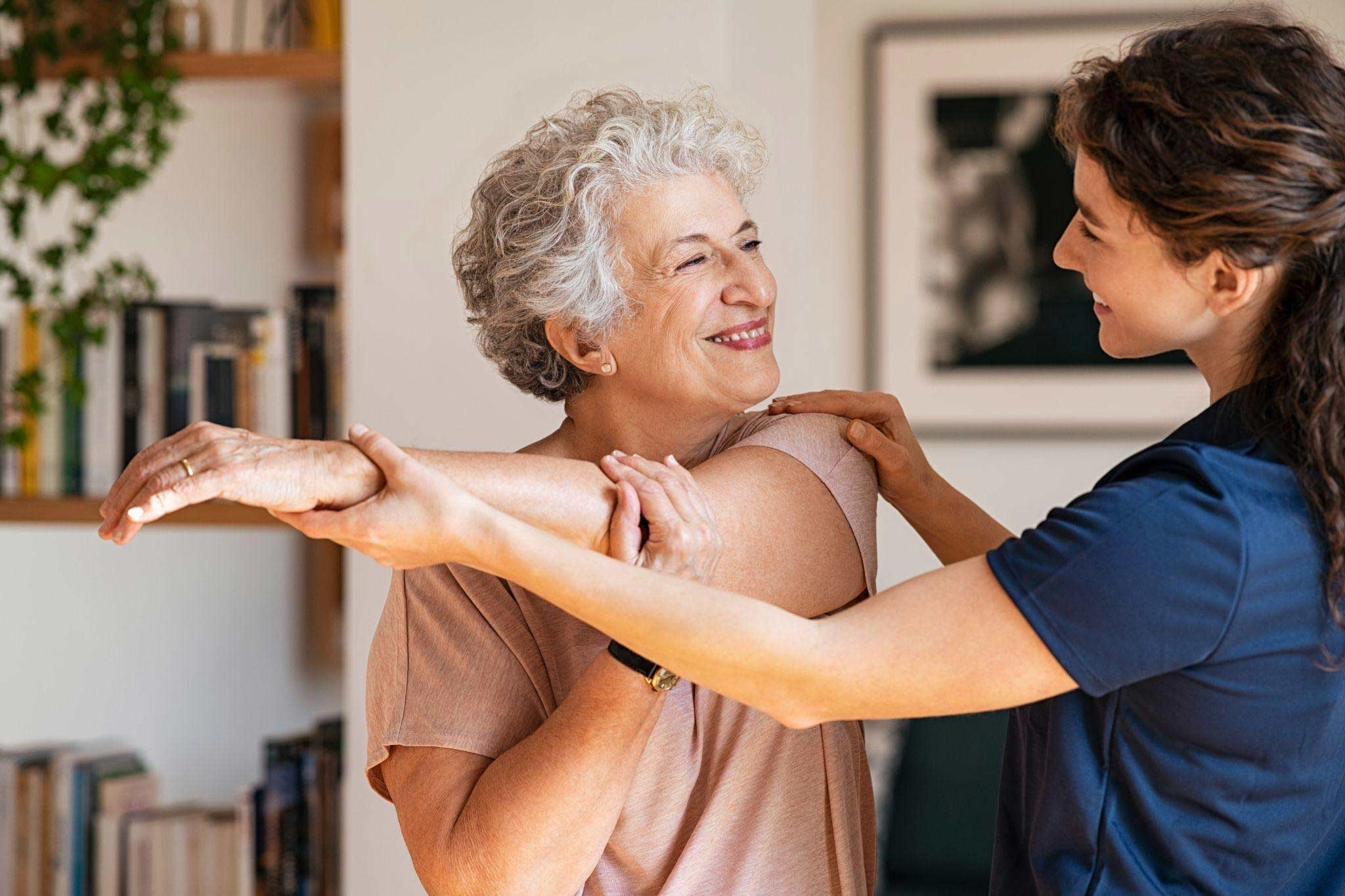 A physiotherapist guiding an elderly woman through a therapeutic exercise session