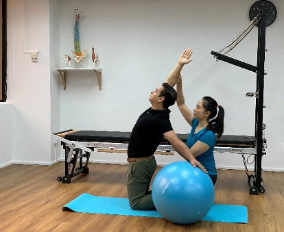 A physiotherapist guiding a patient through a clinical Pilates exercise.