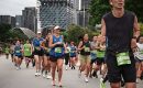 Group of marathon runners in Singapore city during race, wearing bibs and athletic gear.