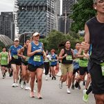 Group of marathon runners in Singapore city during race, wearing bibs and athletic gear.